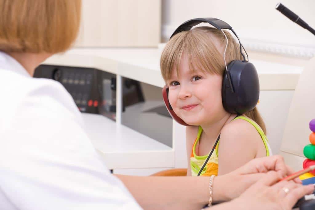 A child receiving a hearing screening in a clinical setting.  