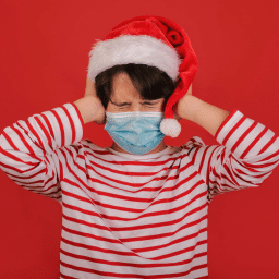 child in santa hat covering ears