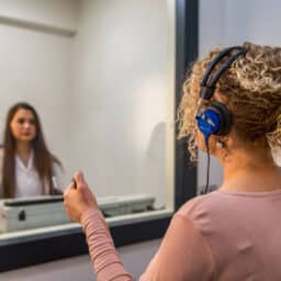 An audiologist performs a hearing test on a patient in a sound booth.