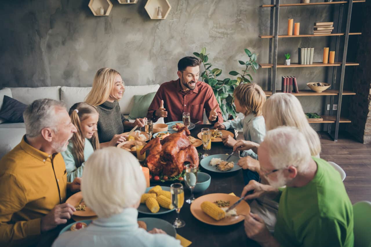 Large, cheerful family sitting down to a Thanksgiving dinner.