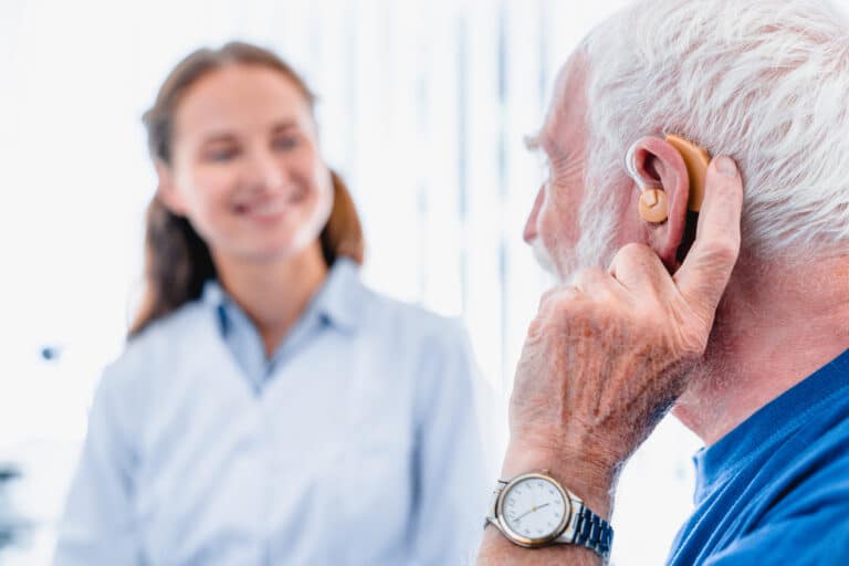 Older man with a hearing aid talking with his medical provider.