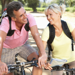 A Caucasian man and woman sitting on bicycles smiling at each other.