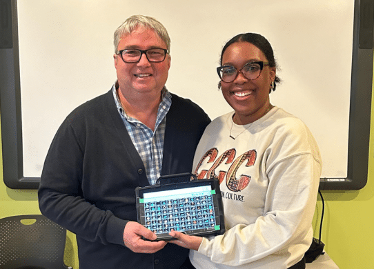 Man and woman holding AAC tablet and smiling
